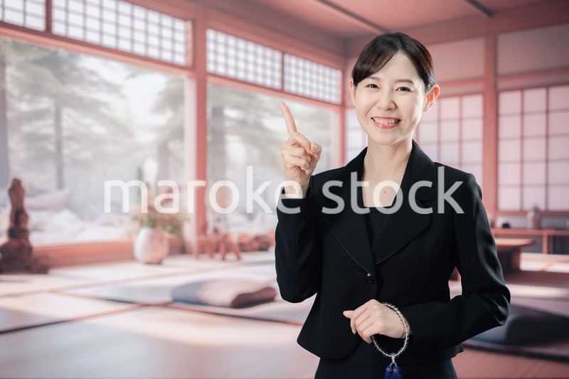 喪服で指を指しアドバイスをする女性