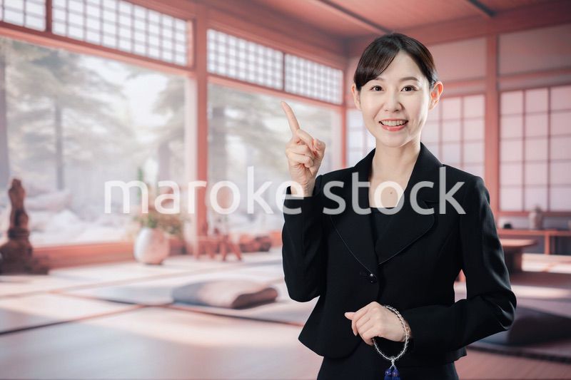 喪服で指を指しアドバイスをする女性