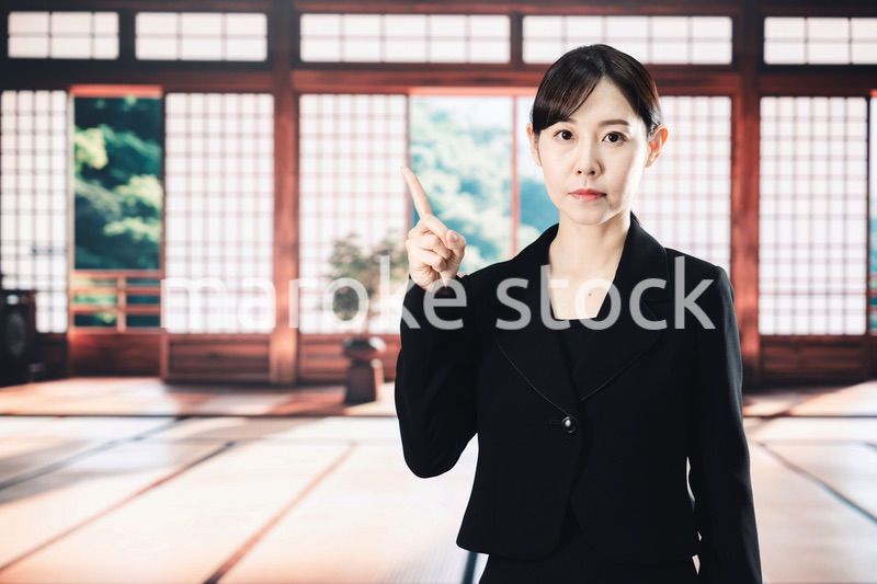 喪服で指を指しアドバイスをする女性