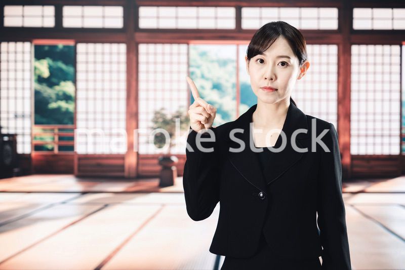 喪服で指を指しアドバイスをする女性