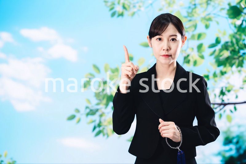 喪服で指を指しアドバイスをする女性