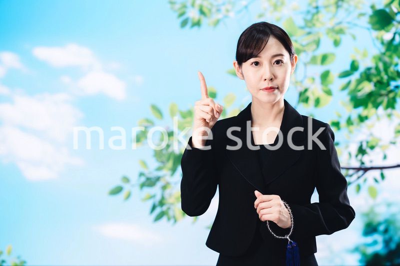 喪服で指を指しアドバイスをする女性