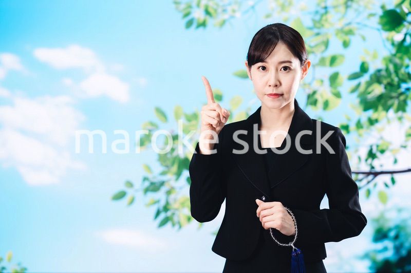 喪服で指を指しアドバイスをする女性