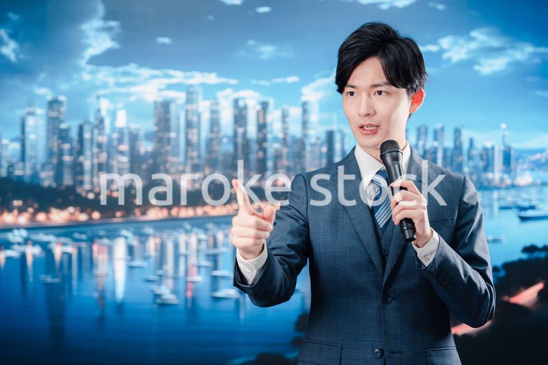 野外でマイクを使って話すスーツを着た男性