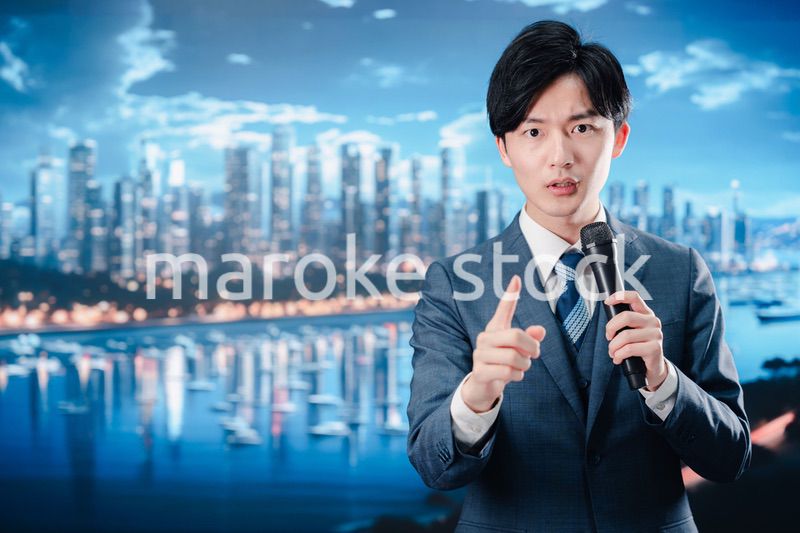 野外でマイクを使って話すスーツを着た男性