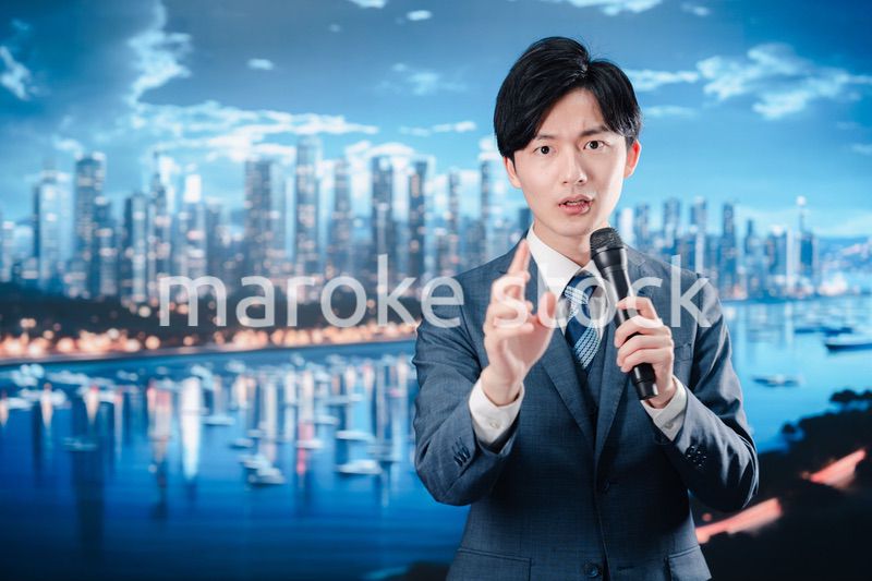 野外でマイクを使って話すスーツを着た男性