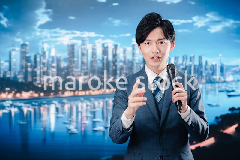 野外でマイクを使って話すスーツを着た男性