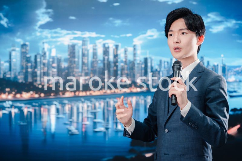 野外でマイクを使って話すスーツを着た男性