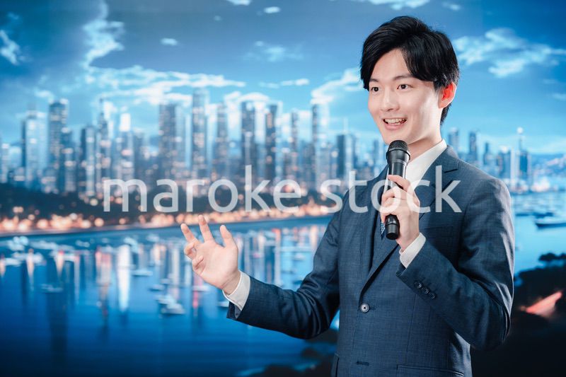野外でマイクを使って話すスーツを着た男性