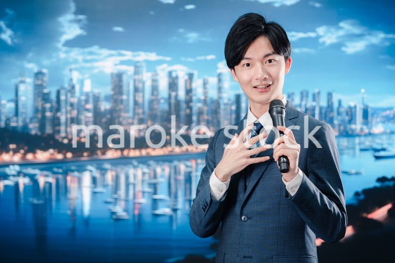 野外でマイクを使って話すスーツを着た男性