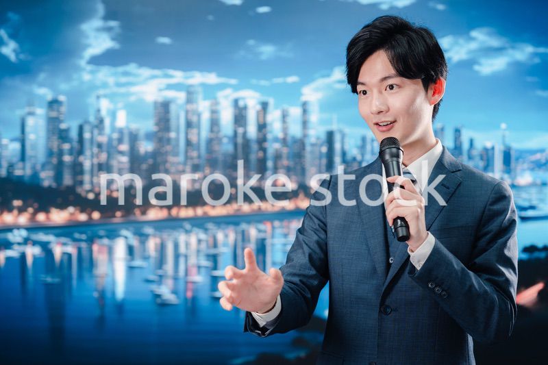 野外でマイクを使って話すスーツを着た男性