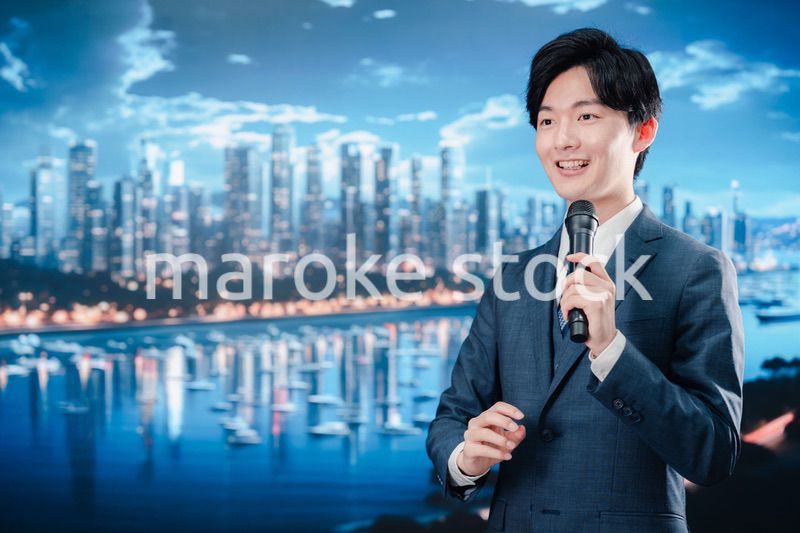 野外でマイクを使って話すスーツを着た男性