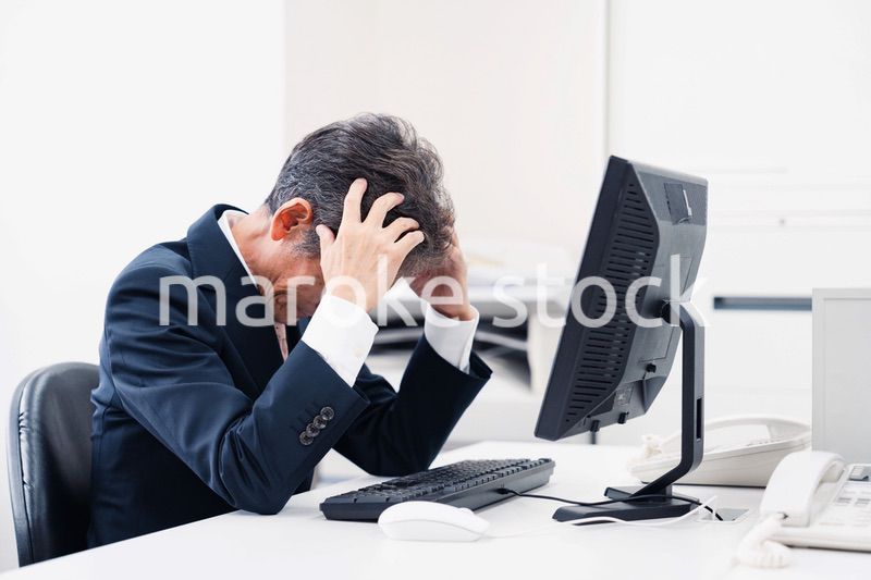 頭を抱えるミドルマネジメントの男性