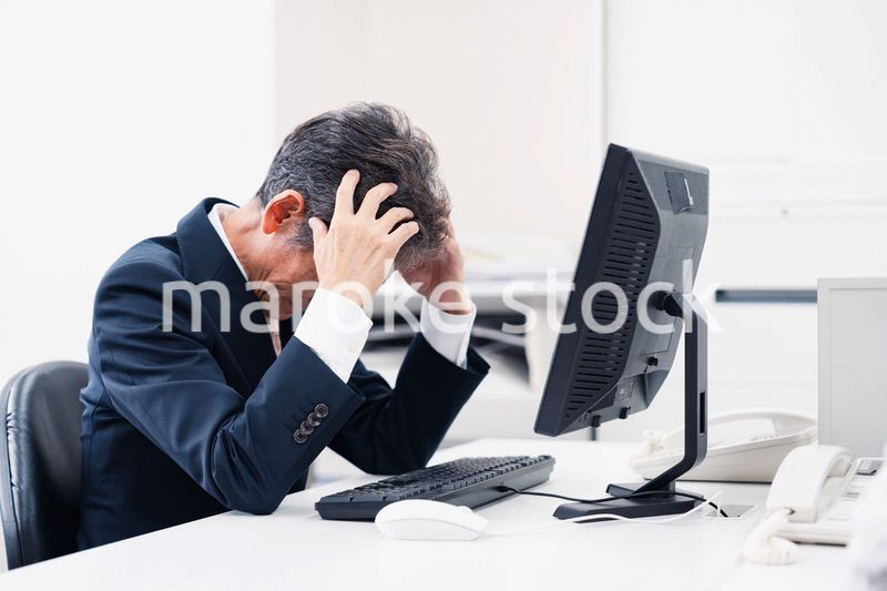 頭を抱えるミドルマネジメントの男性