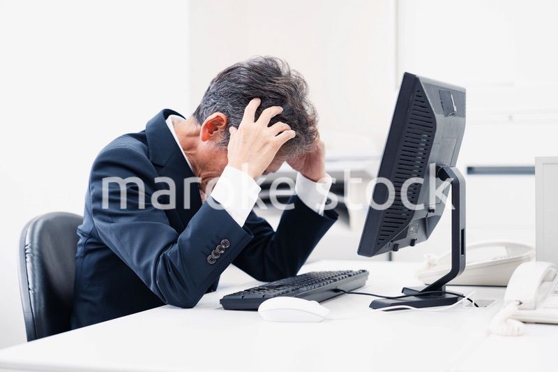 頭を抱えるミドルマネジメントの男性