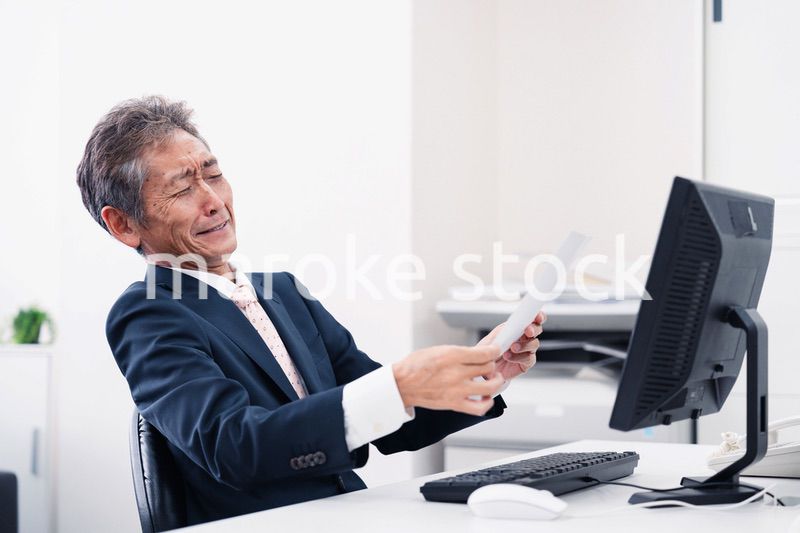 老眼で書類が見づらい高齢のビジネスマン