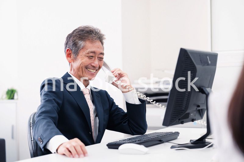 笑顔で電話をするミドルマネジメントの男性
