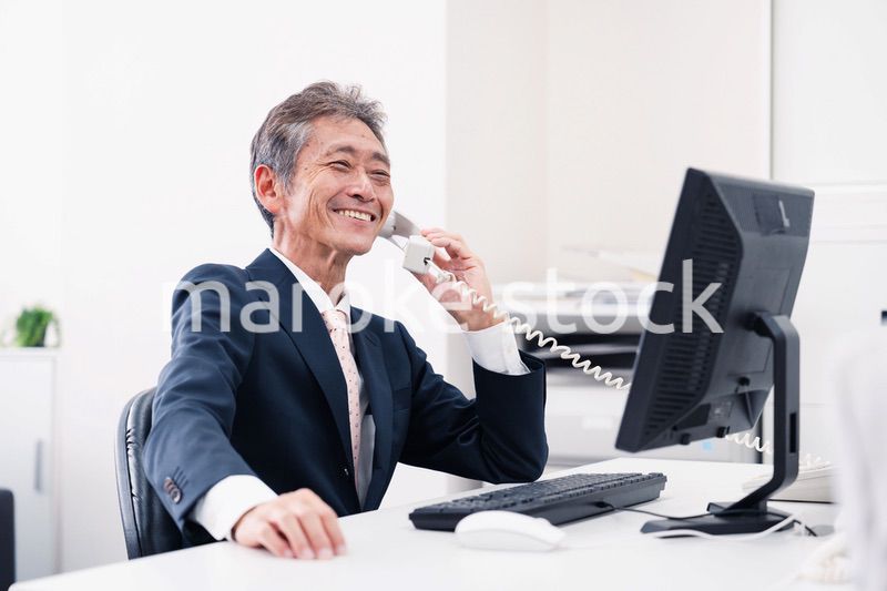 笑顔で電話をするミドルマネジメントの男性