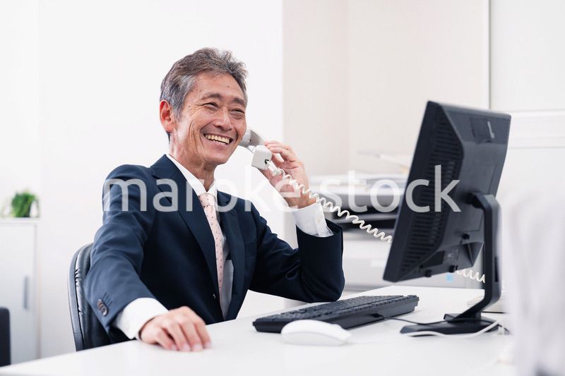笑顔で電話をするミドルマネジメントの男性
