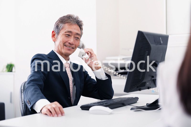 笑顔で電話をするミドルマネジメントの男性