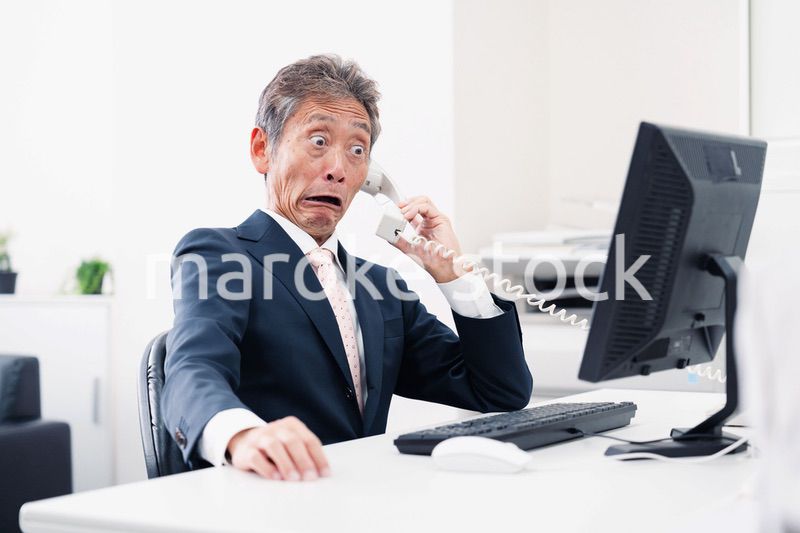 電話で驚く管理職の男性