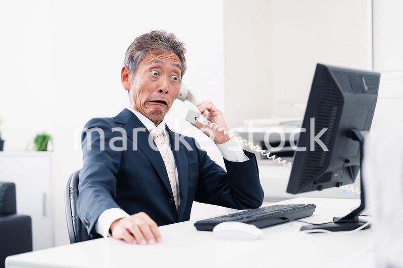 電話で驚く管理職の男性