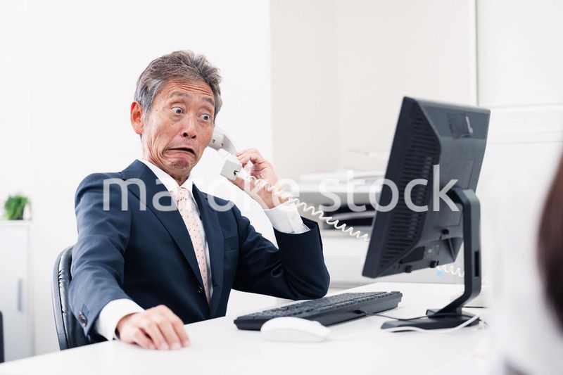 電話で驚く管理職の男性