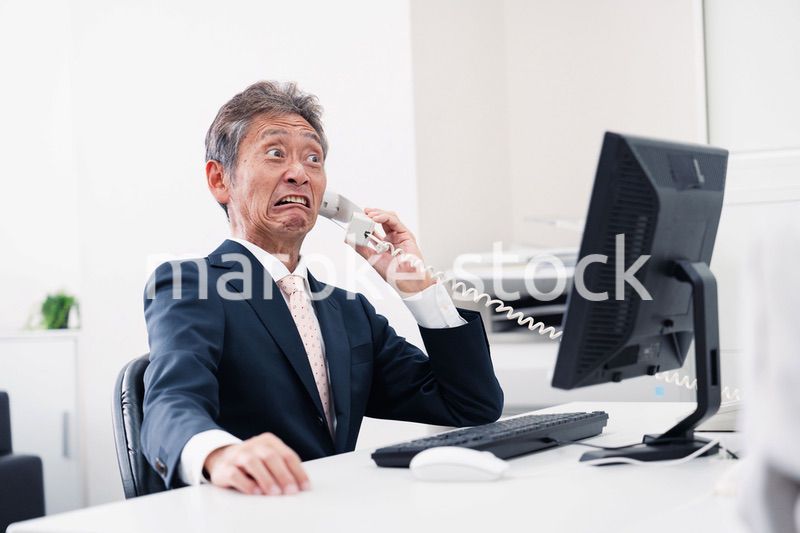 電話で驚く管理職の男性