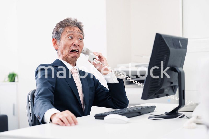 電話で驚く管理職の男性