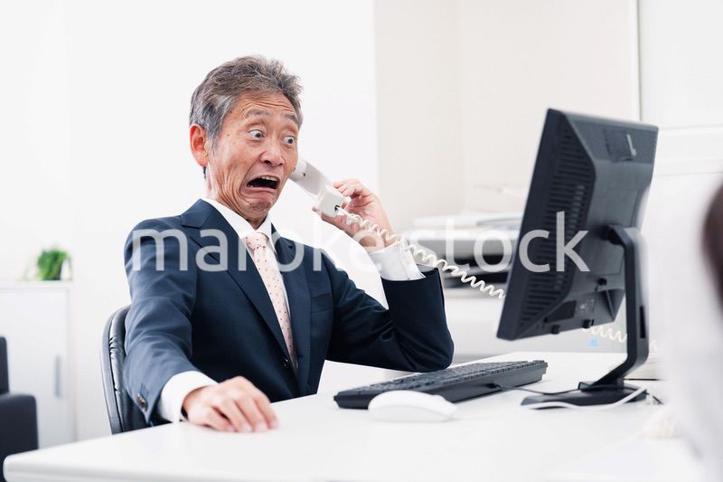 電話で驚く管理職の男性