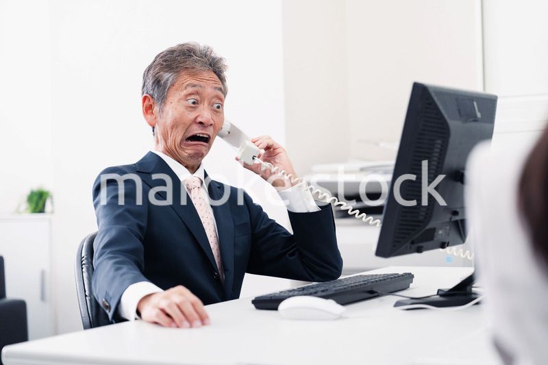 電話で驚く管理職の男性