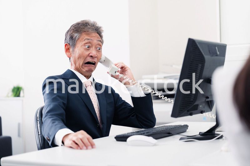 電話で驚く管理職の男性