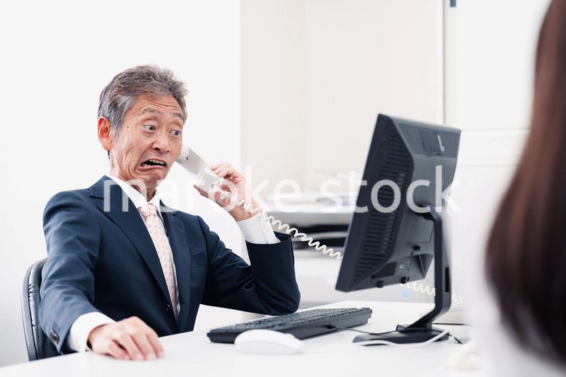 電話で驚く管理職の男性