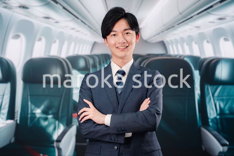 飛行機の機内で腕を組むビジネスマン