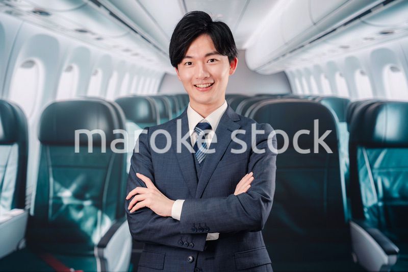 飛行機の機内で腕を組むビジネスマン