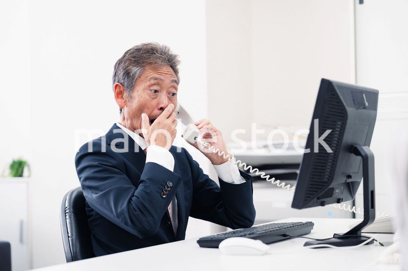 電話で驚く管理職の男性