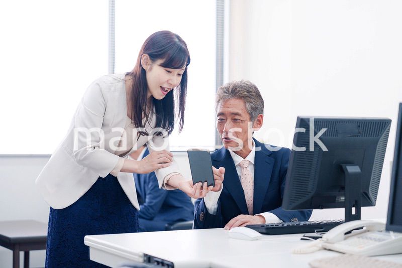 上司にスマホを見せる女性社員