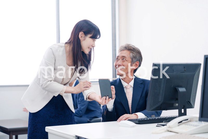 上司にスマホを見せる女性社員