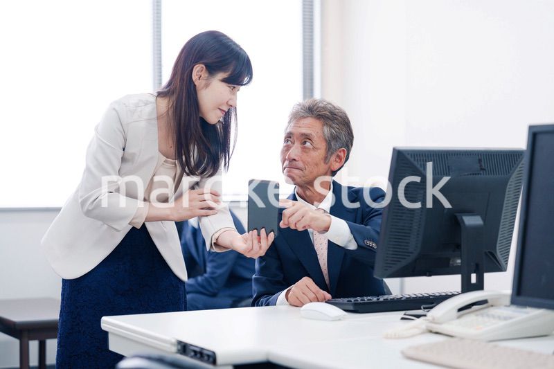 上司にスマホを見せる女性社員