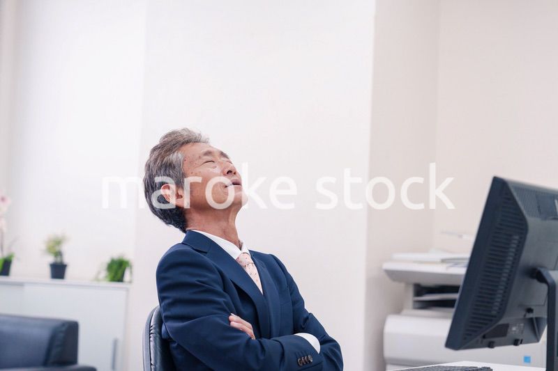 オフィスで腕を組んで悩む中年の上司