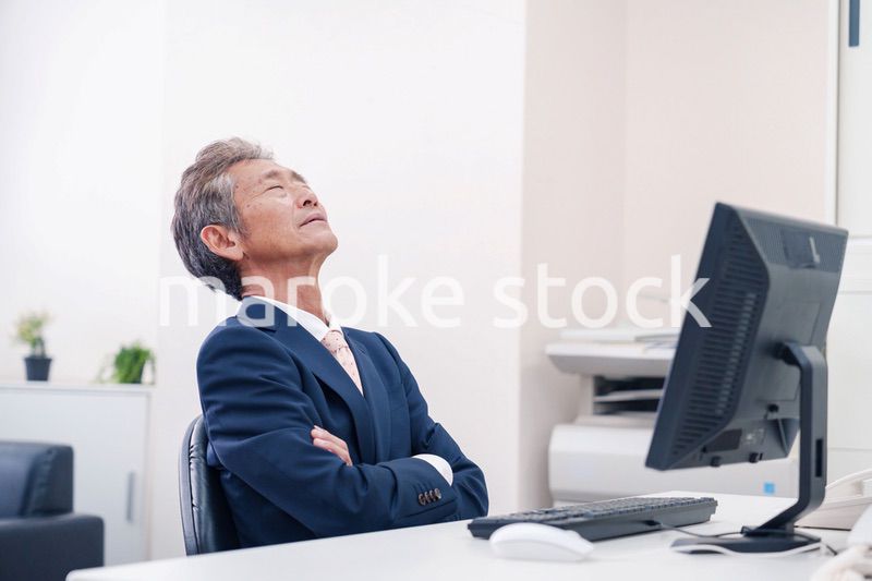 オフィスで腕を組んで悩む中年の上司