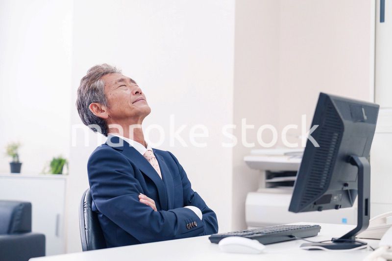 オフィスで腕を組んで悩む中年の上司