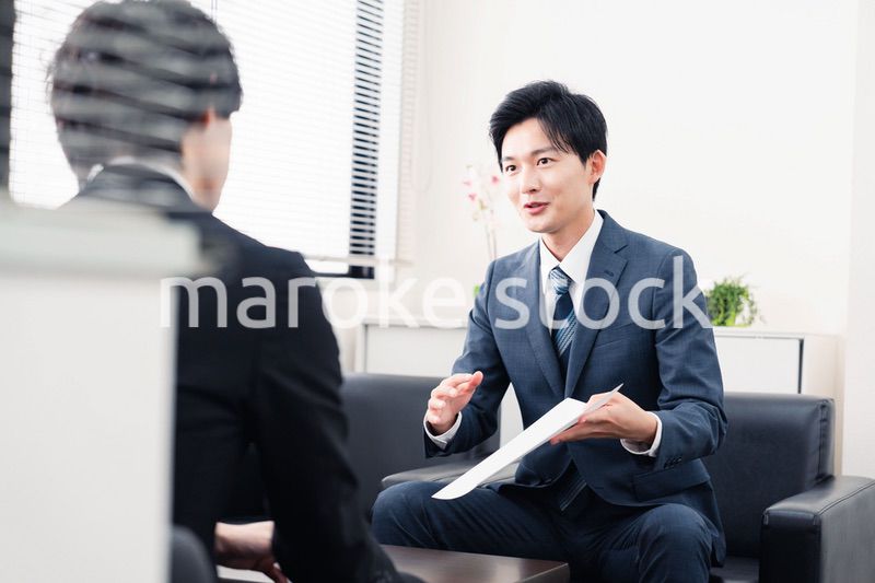 商談で書類を提示するビジネスマン