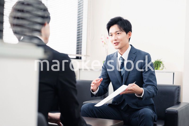商談で書類を提示するビジネスマン