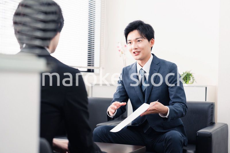 商談で書類を提示するビジネスマン