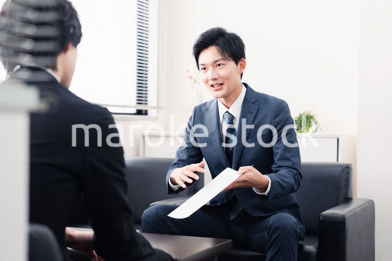 商談で書類を提示するビジネスマン