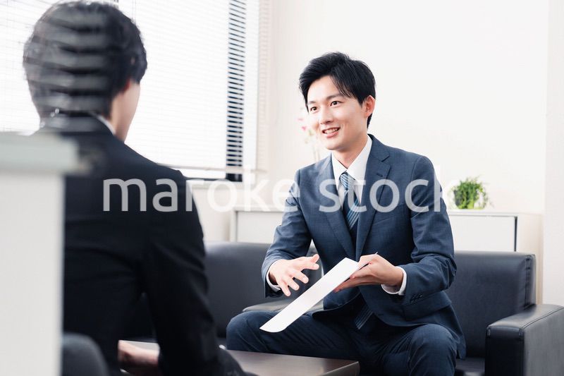 商談で書類を提示するビジネスマン