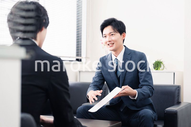 商談で書類を提示するビジネスマン