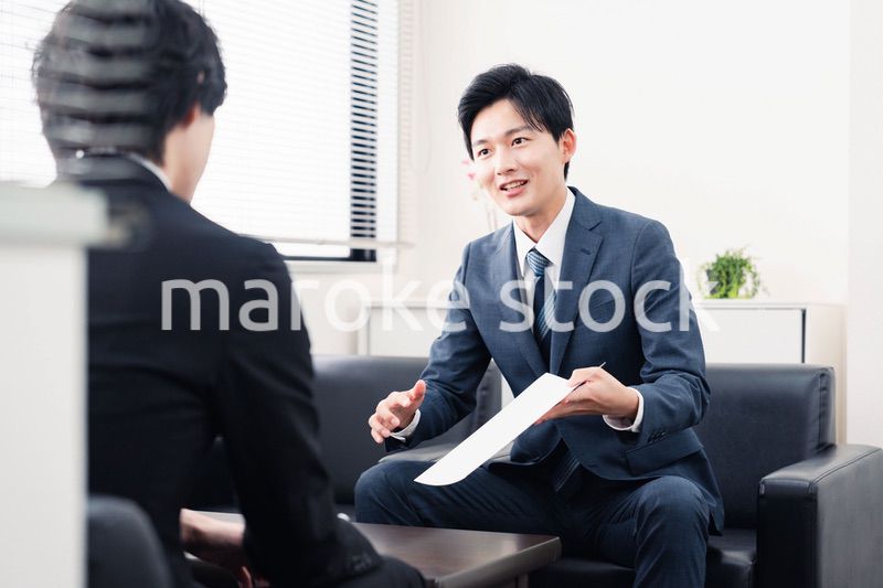 商談で書類を提示するビジネスマン