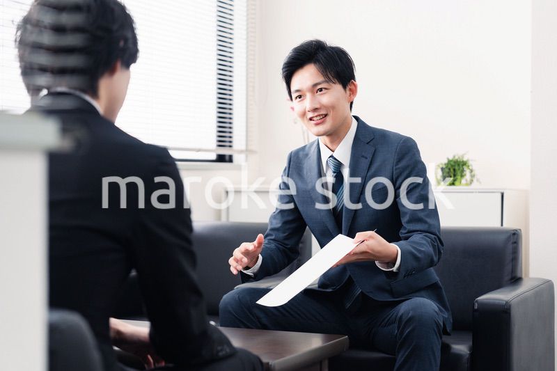商談で書類を提示するビジネスマン